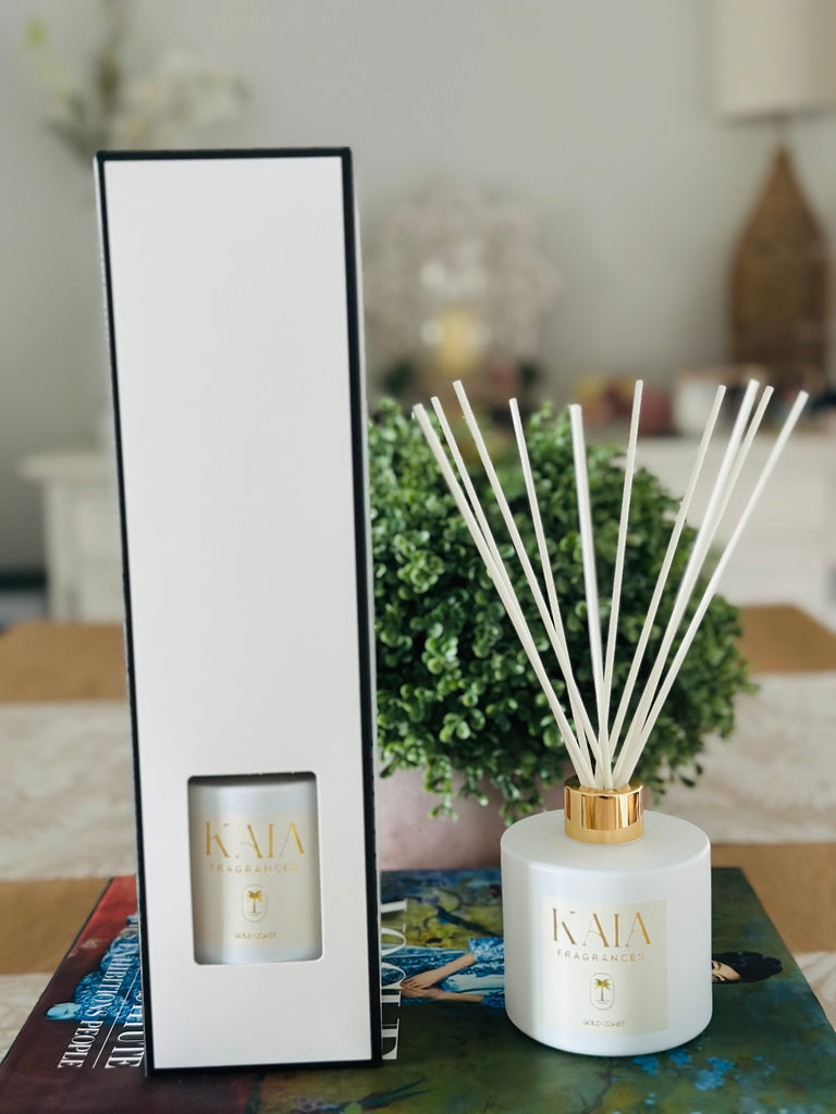 A reed diffuser in white packaging with a black border and another diffuser out of its packaging next to it