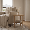 KAIA Unwind Diffuser with Beige armchair with a blanket and wooden side table with decor items in a room.