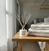 KAIA Balance Diffuser on a wooden table with folded towels in a bedroom setting