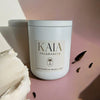 A white candle called 'Vanilla Gelatissimo' on a pink bench with vanilla gelato next to it